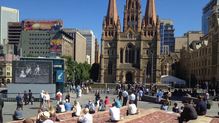People gathered in front of a screen in Federation Square.