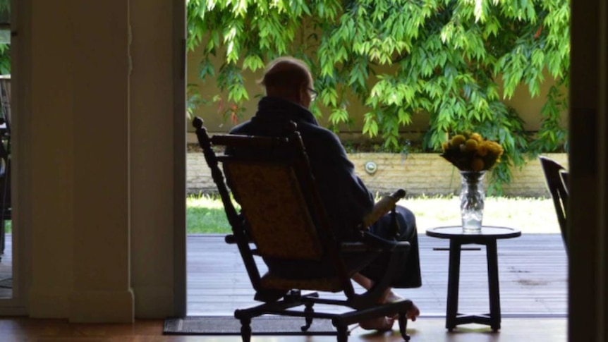 An aged care resident sits in a chair.