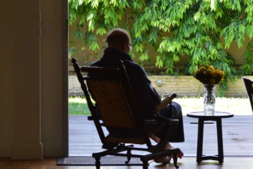 An aged care resident sits in a chair.