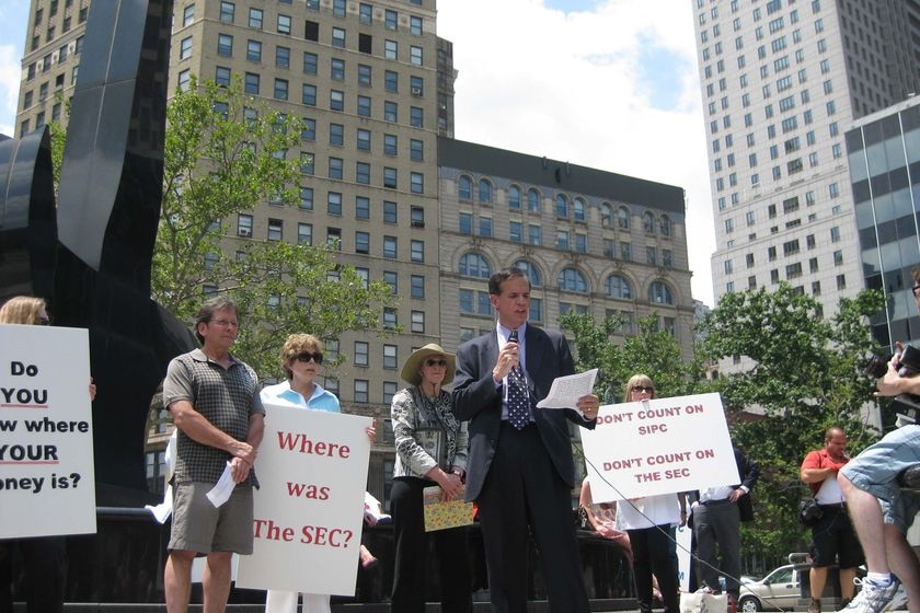 Victims of Wall St fraudster Bernie Madoff gather outside court with placards