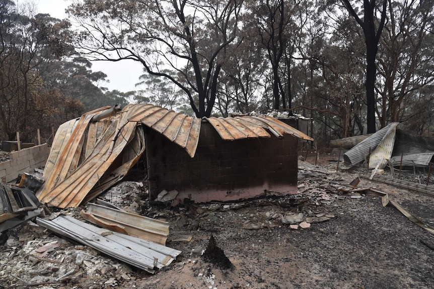 A collection of metal sheets, burnt bricks and debris where a house once stood.