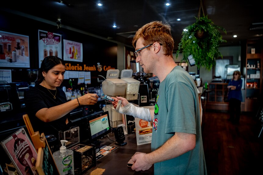 A young man buying a coffee.