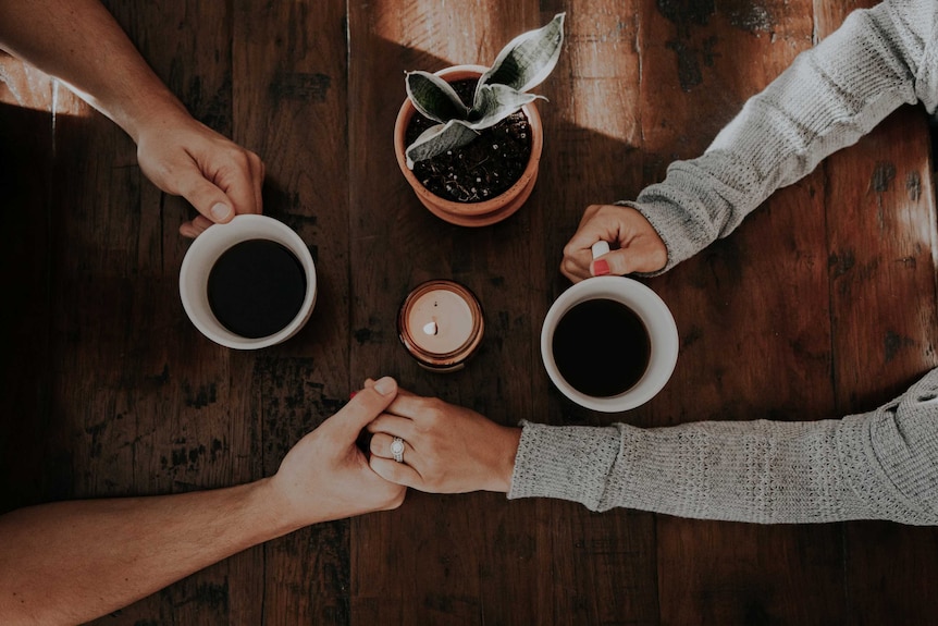 Two people holding each other's hands at a table