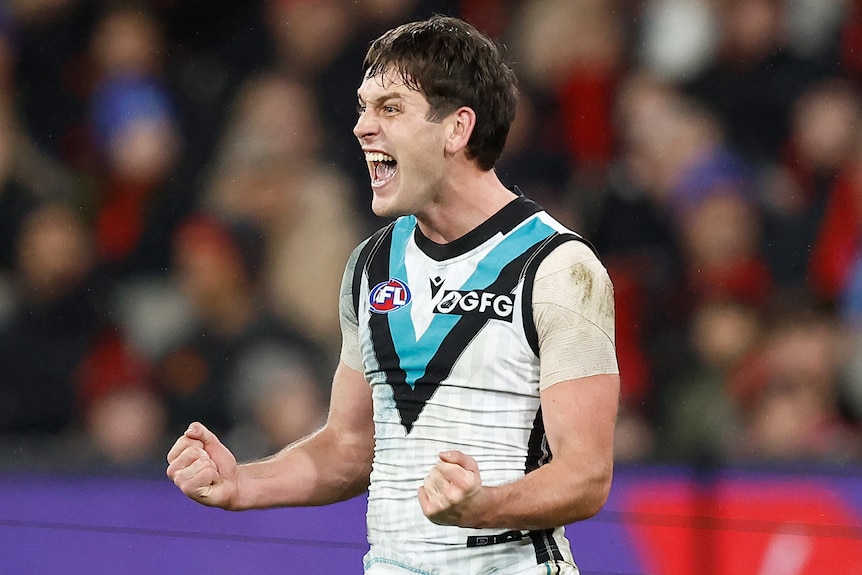 A Port Adelaide forward pumps his fists in delight after kicking a key goal during a game at the MCG.