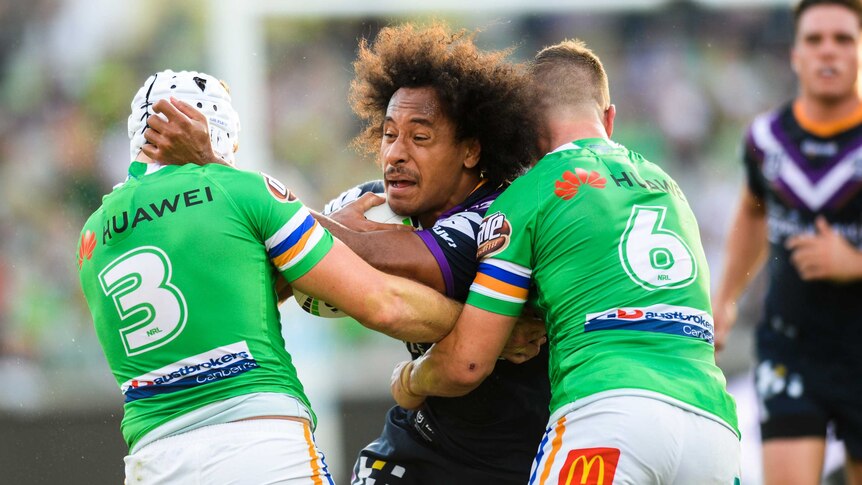 Felis Kaufusi is tackled by two Canberra Raiders players while trying to stay on his feet.