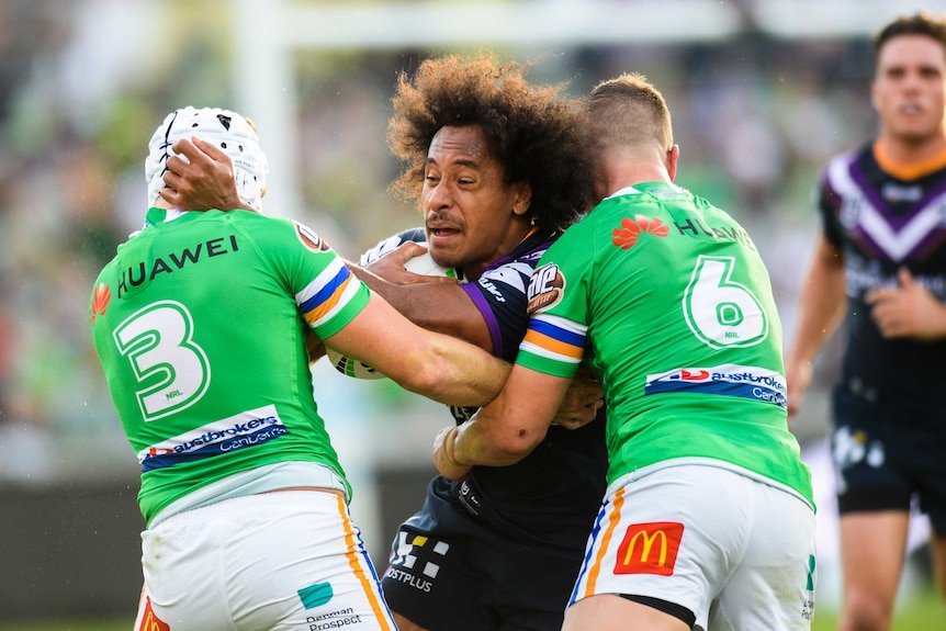 Felis Kaufusi is tackled by two Canberra Raiders players while trying to stay on his feet.
