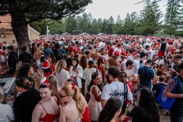 Grandes multidões, lotadas, muitas com chapéus vermelhos, vestidos, árvores ao fundo.