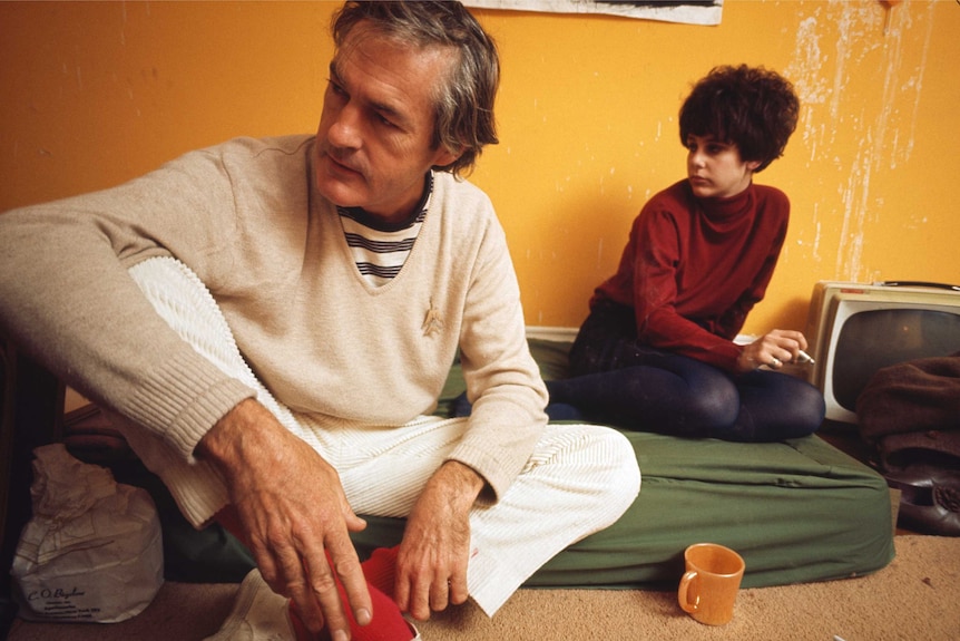 Two men seated on the floor together. 