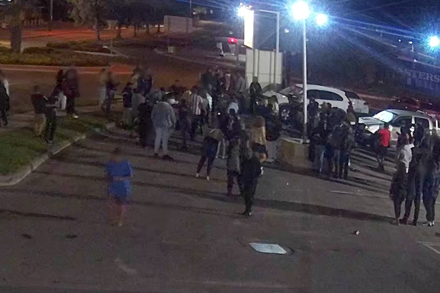 People gathered in a car park outside a pub.