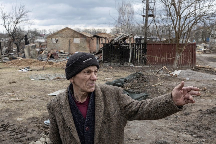 A man points as he stands near destroyed houses in Yahidne, Ukraine.