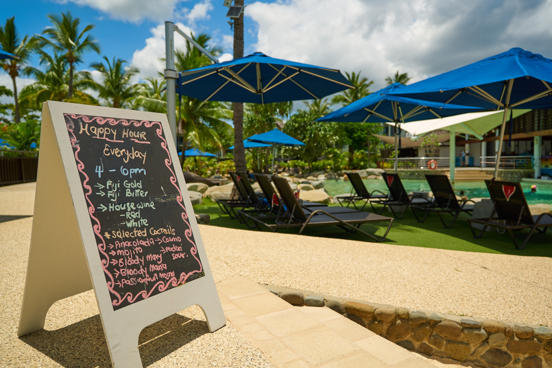 An a-frame chalk board advertises HAPPY HOUR Everyday 4pm - 6pm, listing beers, wines and selected cocktails