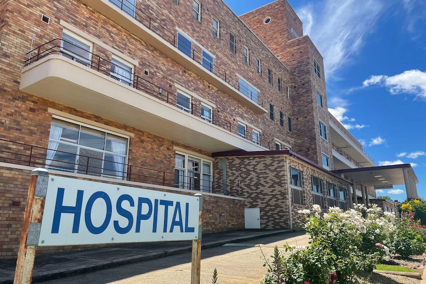 A sign out the front of a brick hospital.