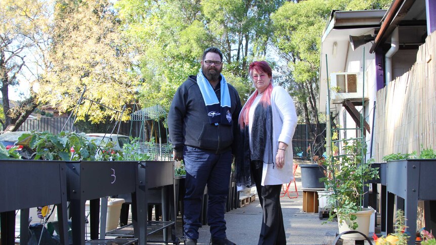 A man and woman stand in the community garden at Craig's Table.