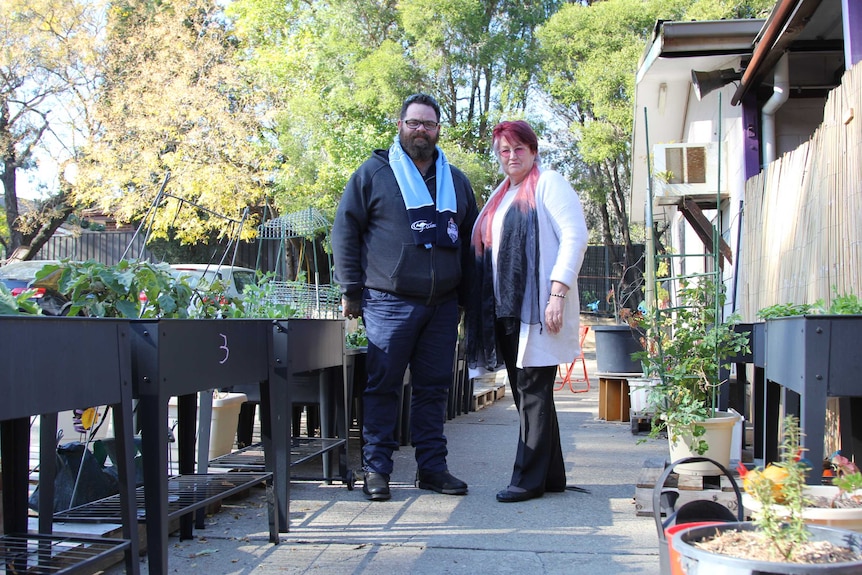 A man and woman stand in the community garden at Craig's Table.