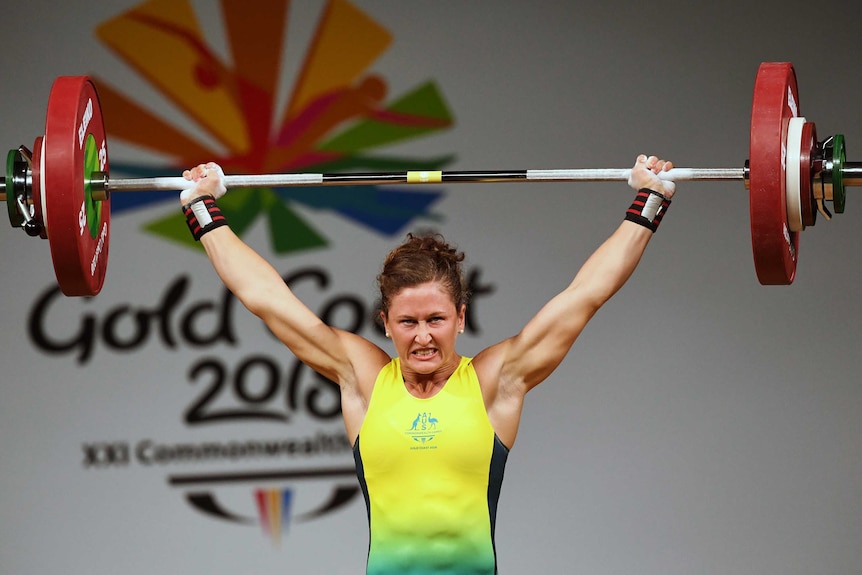 Tia-Clair Toomey holds a barbell over her head.