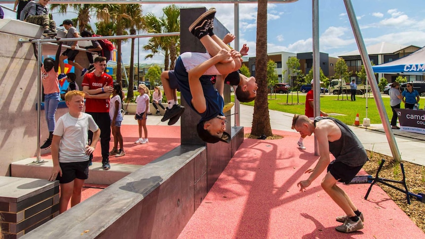 two boys doing backflips off a low height playground wall