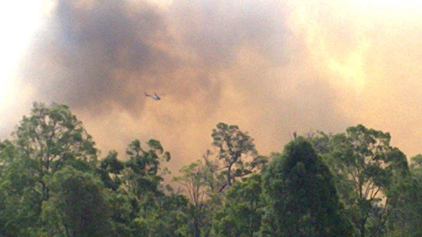 A helicopter flies over a bushfire raging through the Perth suburb of Parkerville