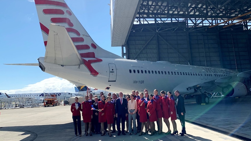 Virgin Australia CEO Ms Hrdlicka and Deputy Prime Minister Michael McCormack pose in front of a plane with Virgin staff.