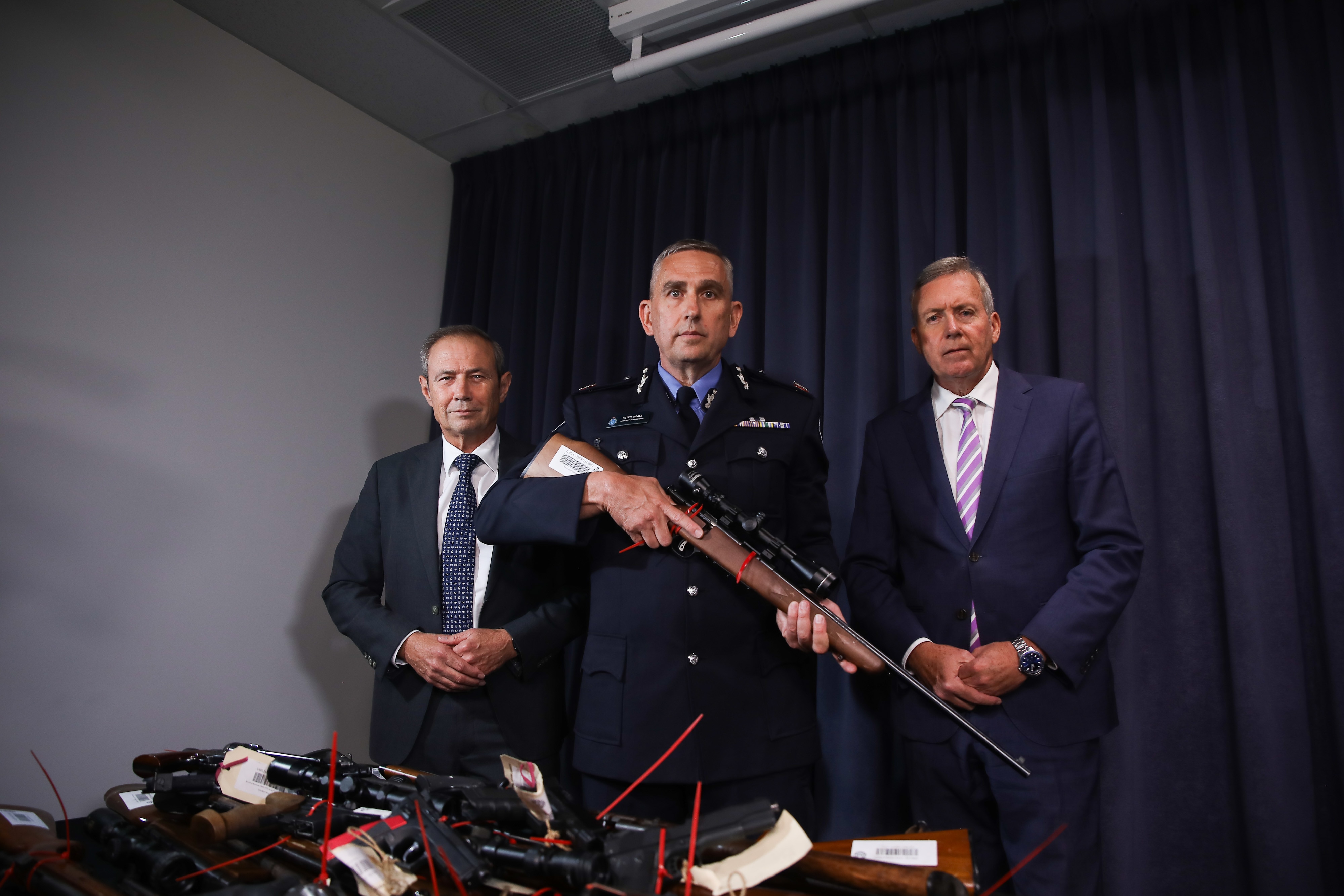 O primeiro-ministro Roger Cook, o vice-comissário da polícia de Washington e o ministro da polícia Reece Whitby portam armas