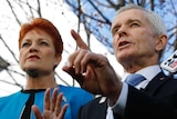 Pauline Hanson and Malcolm Roberts gesture as they speak to the media.