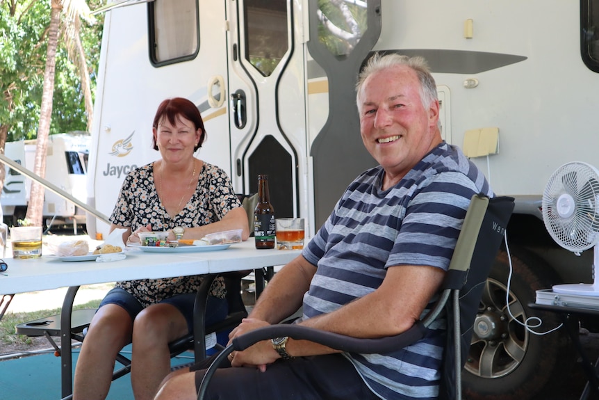 Chris and Yvonne Roff smile as they sit at a table next to their caravan.