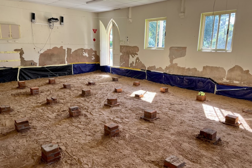 A classroom with the floor covered in mud and bricks lying where the desks once stood.