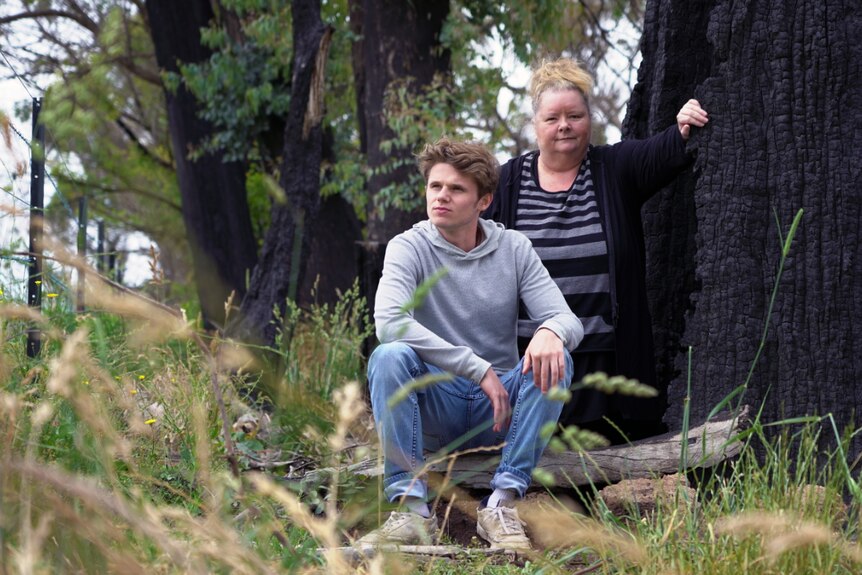 A portrait of Magda Szubanski and 'Egg Boy' in the charred bush with some green regrowth around them