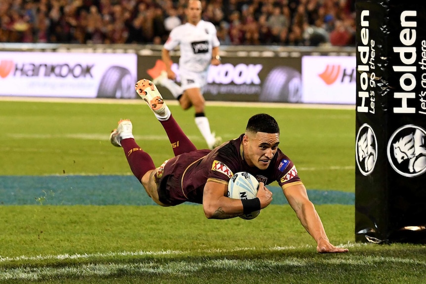 A rugby player dives to score.