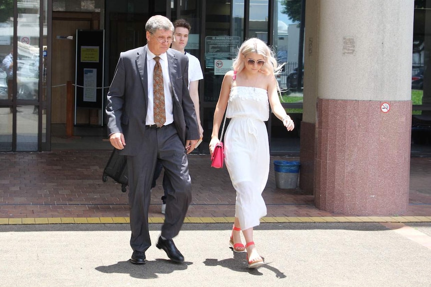 Roger Griffith (left dressed in suit) leaves Cairns Magistrates Court with a woman walking alongside.