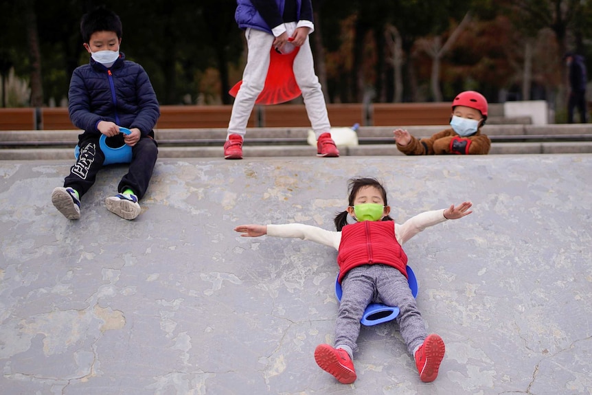 Children wearing face masks play in a skate park