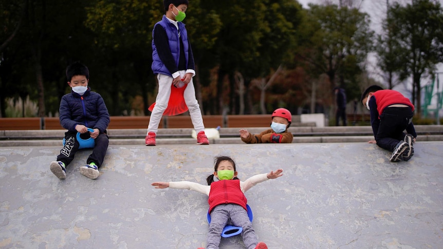 Children wearing face masks play in a skate park