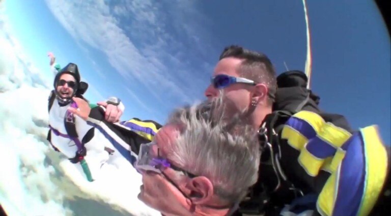 Dos hombres y una mujer haciendo paracaidismo, el primero en tándem.