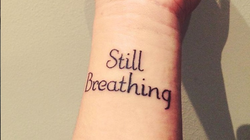 Gabby Bennett's wrist with a tattoo that says "Still Breathing".