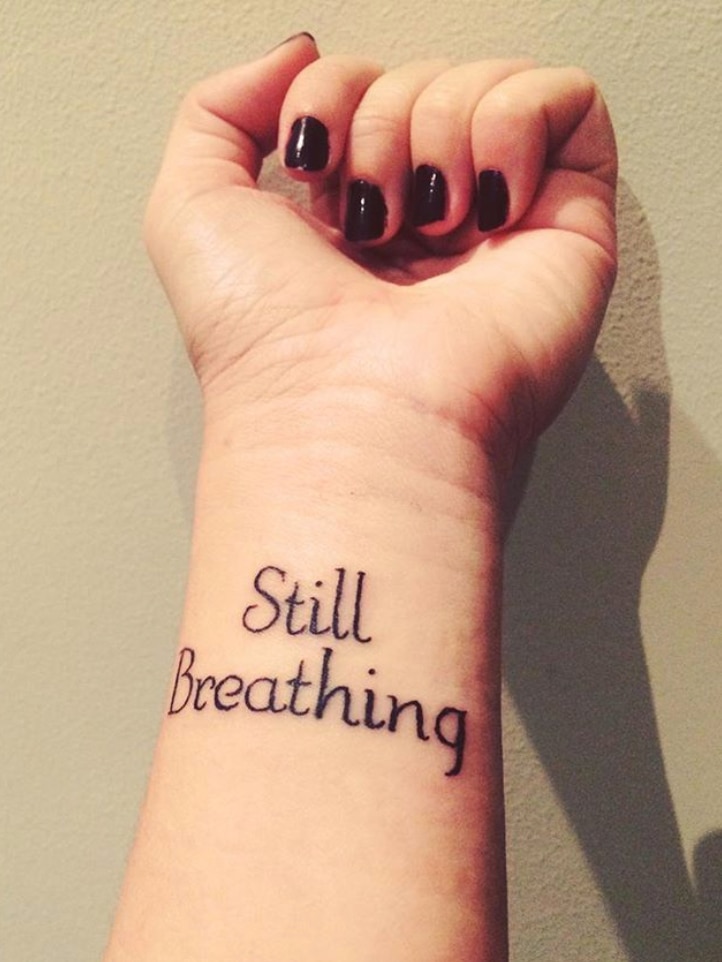 Gabby Bennett's wrist with a tattoo that says "Still Breathing".