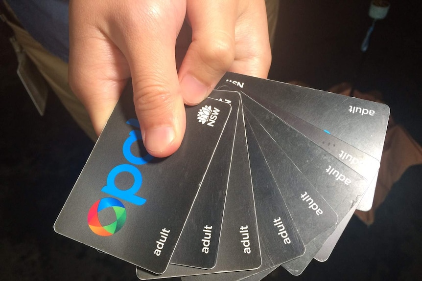 A man holds up eight Opal cards.