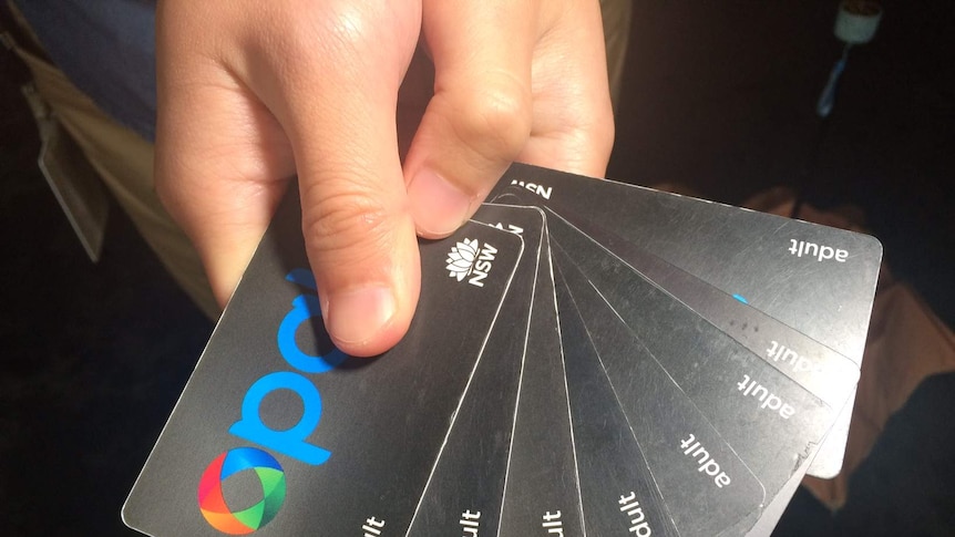 A man holds up eight Opal cards.