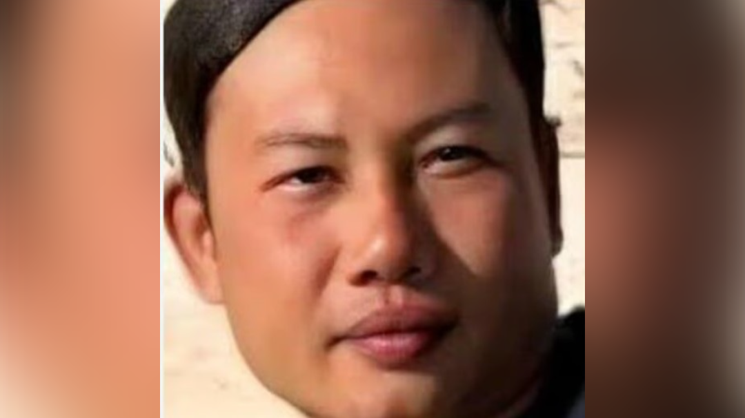 A young Thai man looks towards the camera.