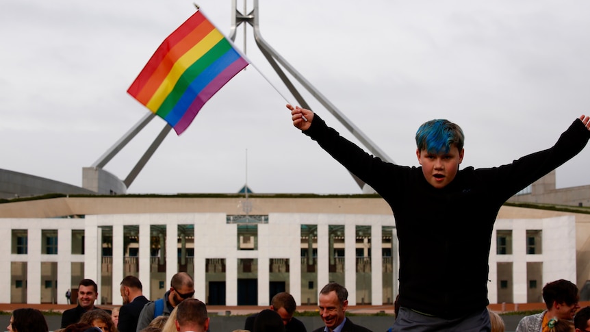 A boy waves a rainbow flag outside Parliament in a demonstration for same-sex marriage.