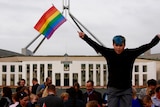 A boy waves a rainbow flag outside Parliament