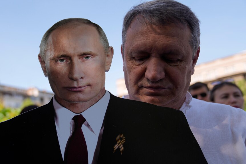 Man holds a cardboard cut out of Vladimir Putin