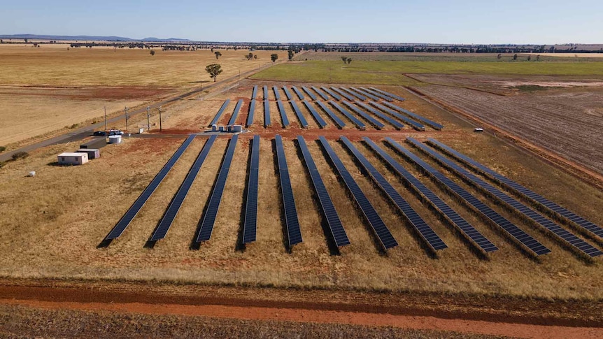 A birds-eye view of a solar filed with solar panels in a countryside