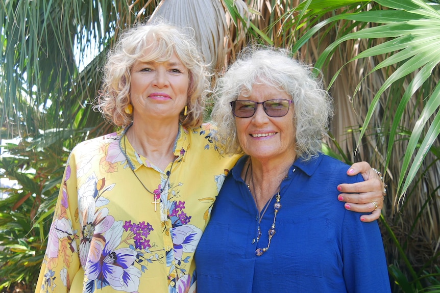 Two woman stand and smile at the camera.