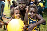 Two young fans with face paint and one older woman at the Tiwi grand final.