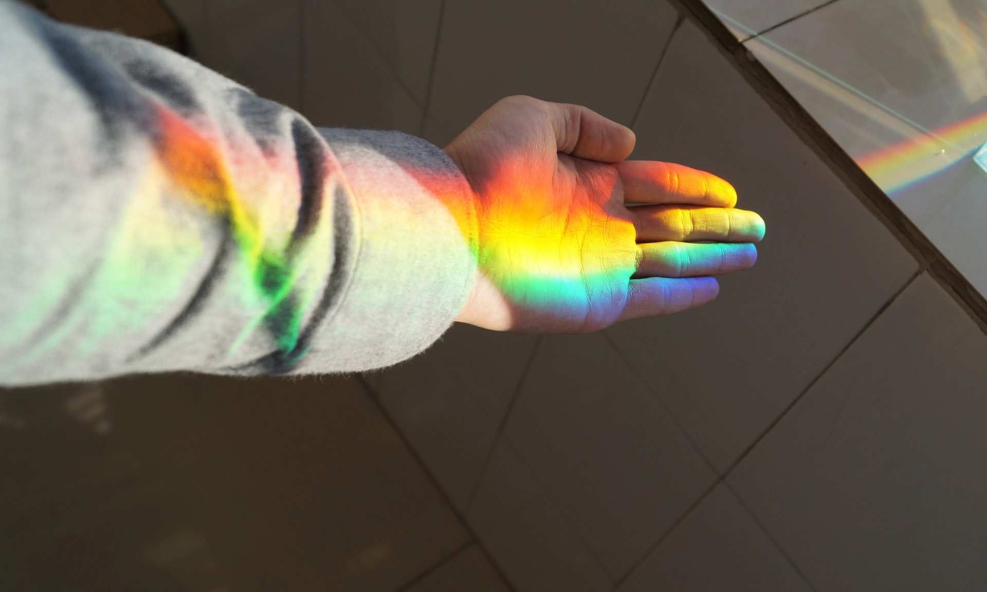 Hand with rainbow light reflecting on it for list of queer and LGBTIQ support numbers and websites in Australia