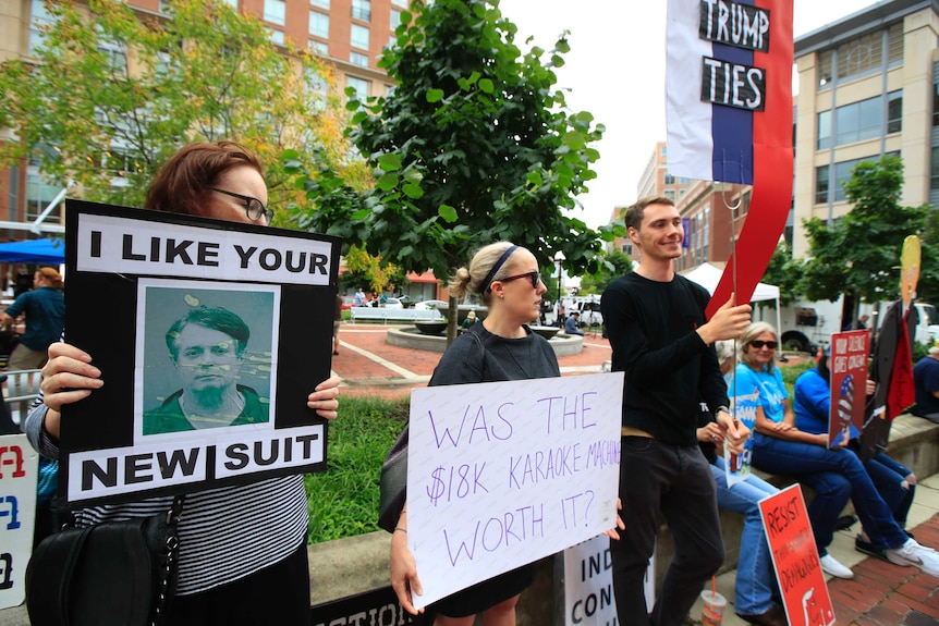 Protesters gathered outside holding signs which read I like your new suit