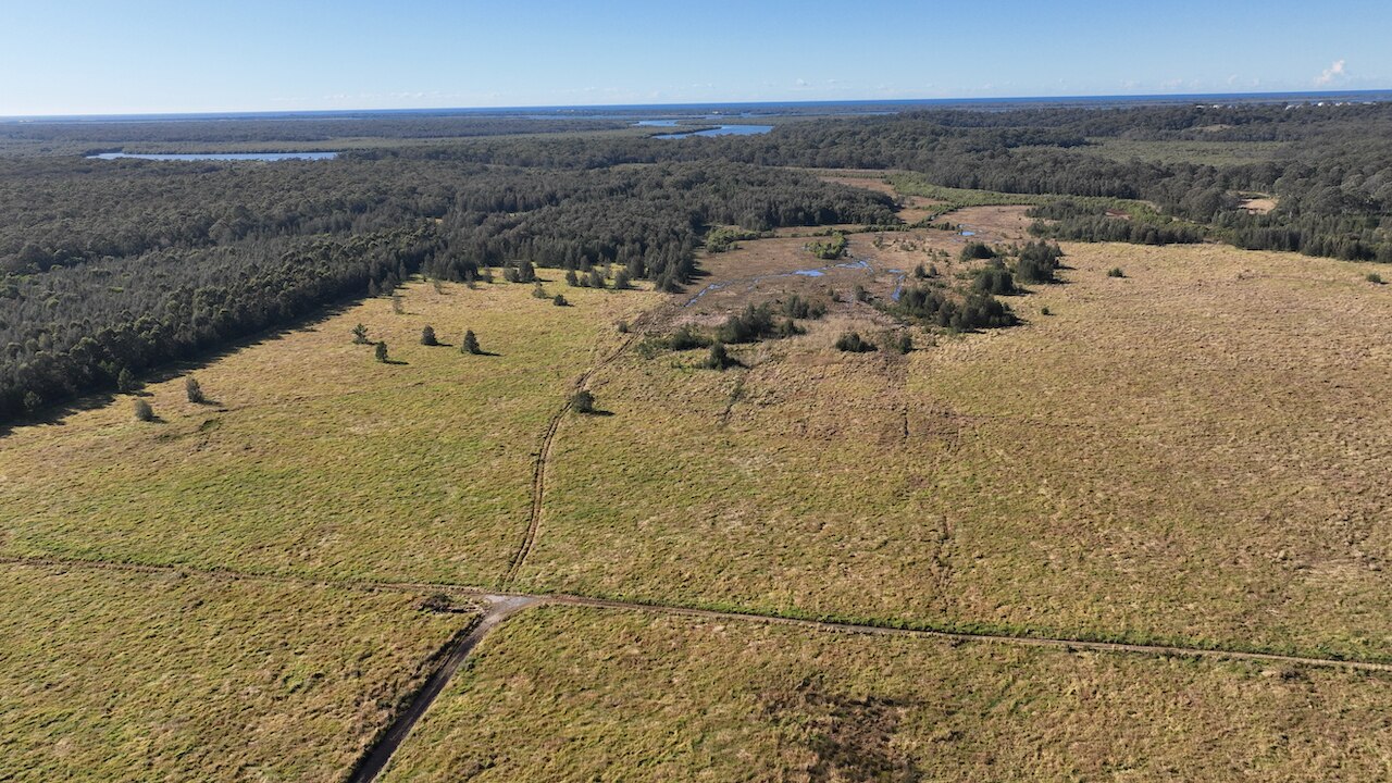 An aerial shot of a greenfield site beneath a clear sky.