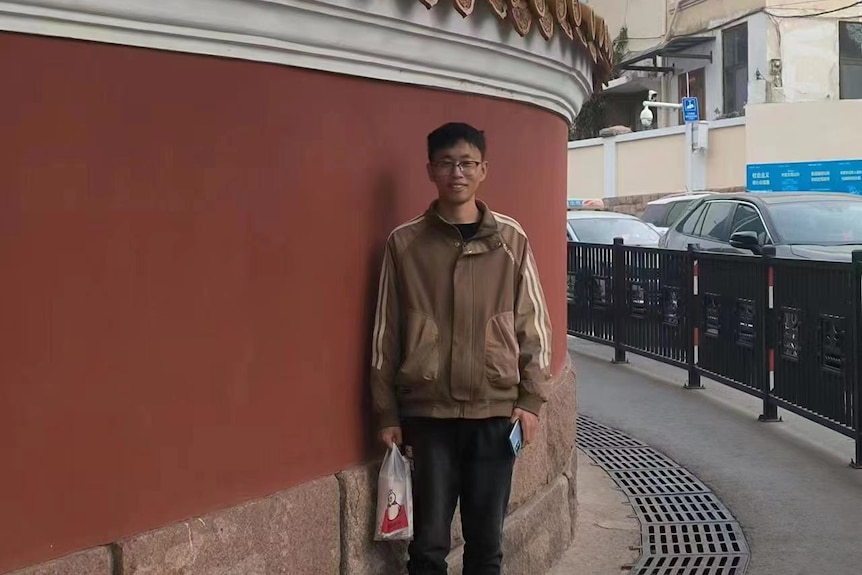 A man posing in front of a red wall