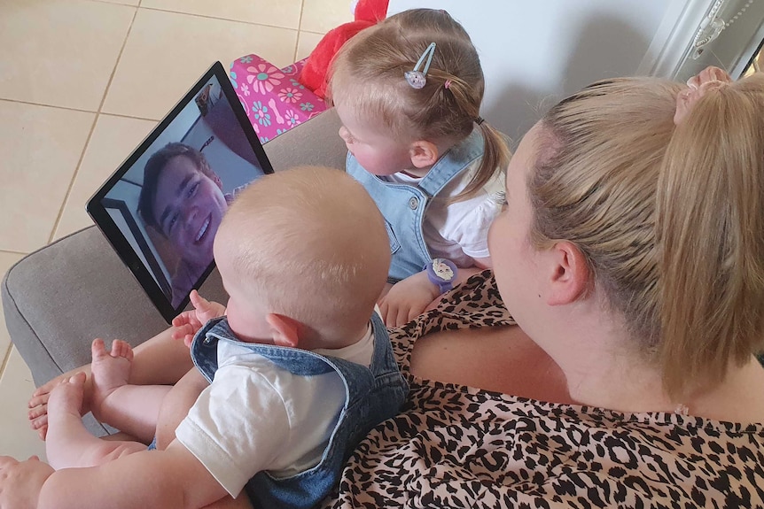 A mum and two children video calling their father