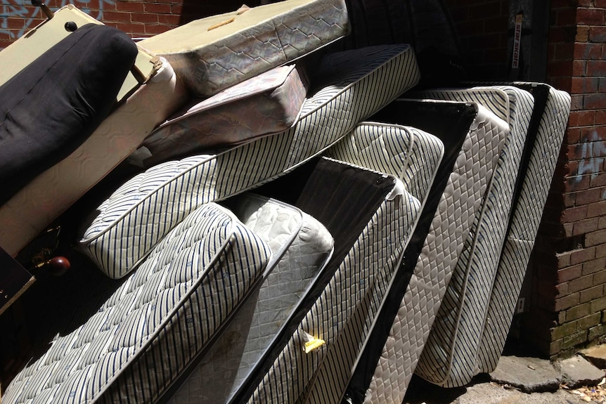 A stack of soiled mattresses left outside a charity donation bin