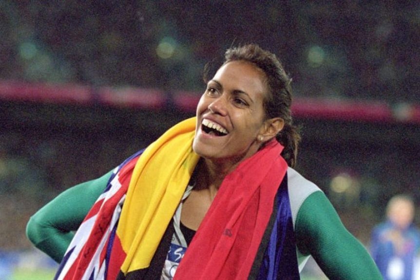 Cathy Freeman with the Aboriginal and Australian flags draped around her neck.